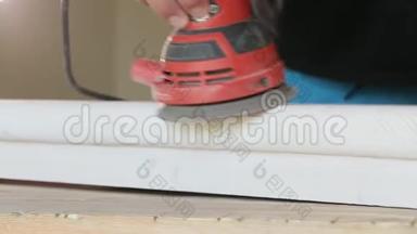 木工在车间特写中用电动砂光机打磨木台阶